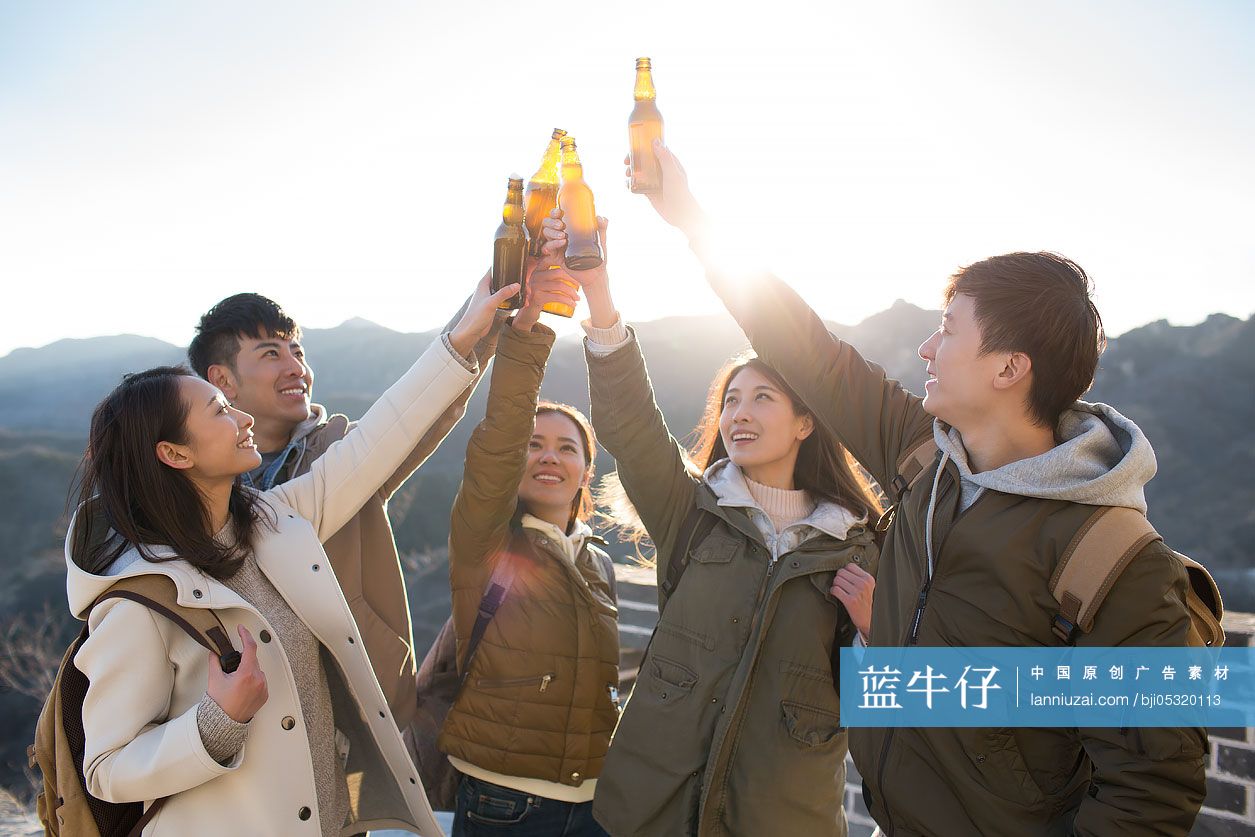 Happy young Chinese friends drinking beer on the Great Wall