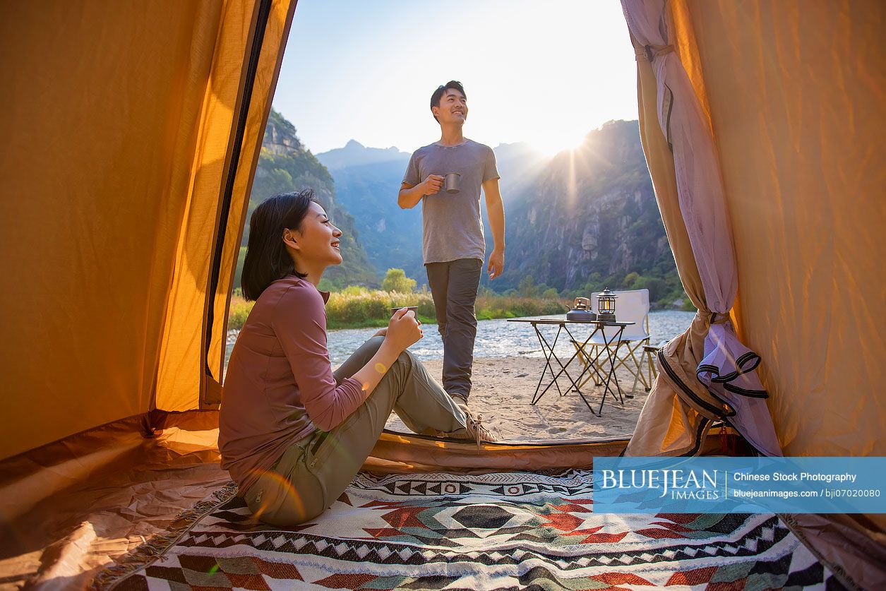 Happy young Chinese couple camping outdoors