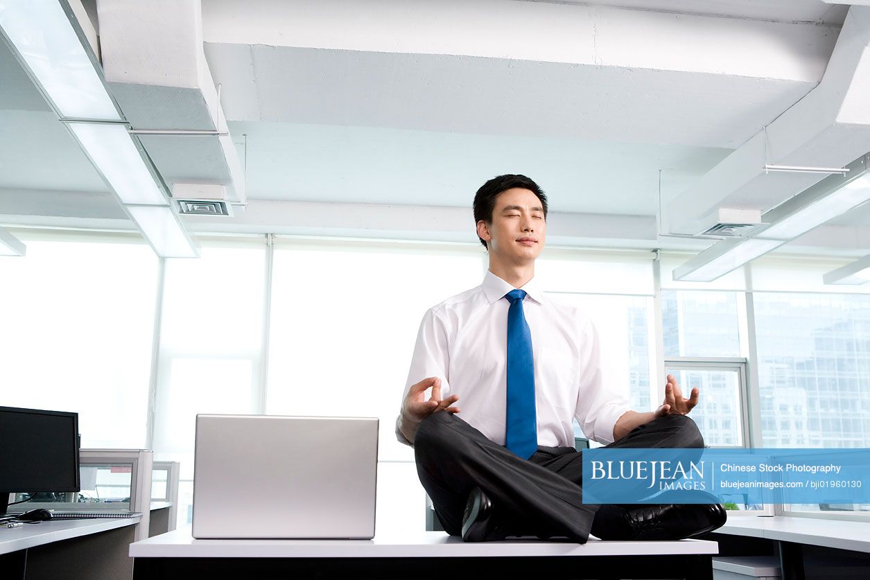 Chinese office worker meditating in the office