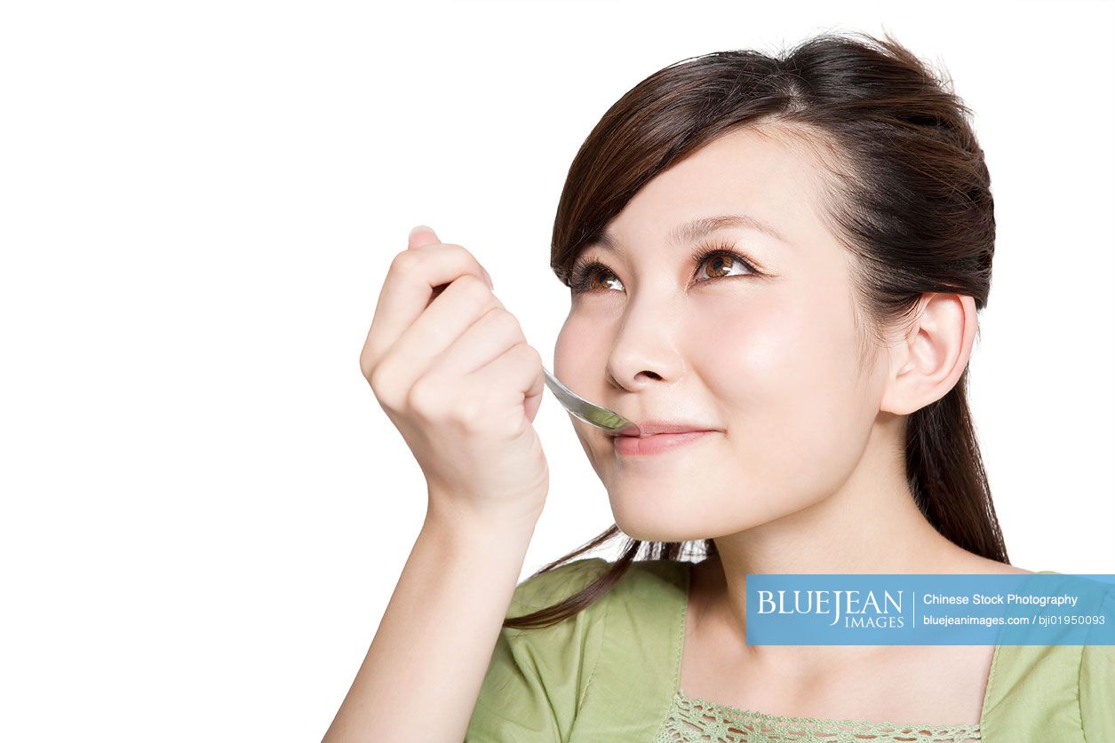 Portrait of young Chinese woman eating from spoon