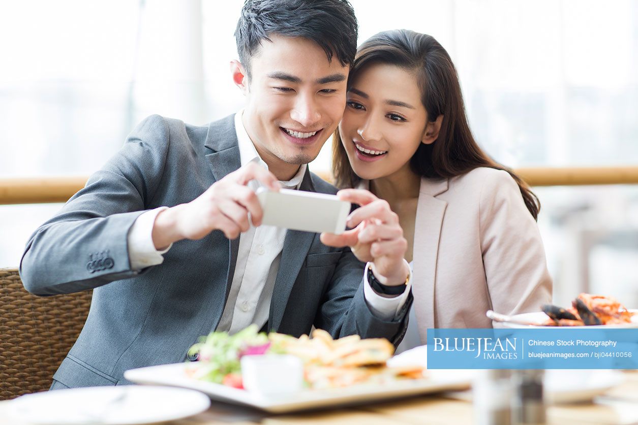 Young Chinese couple photographing in restaurant