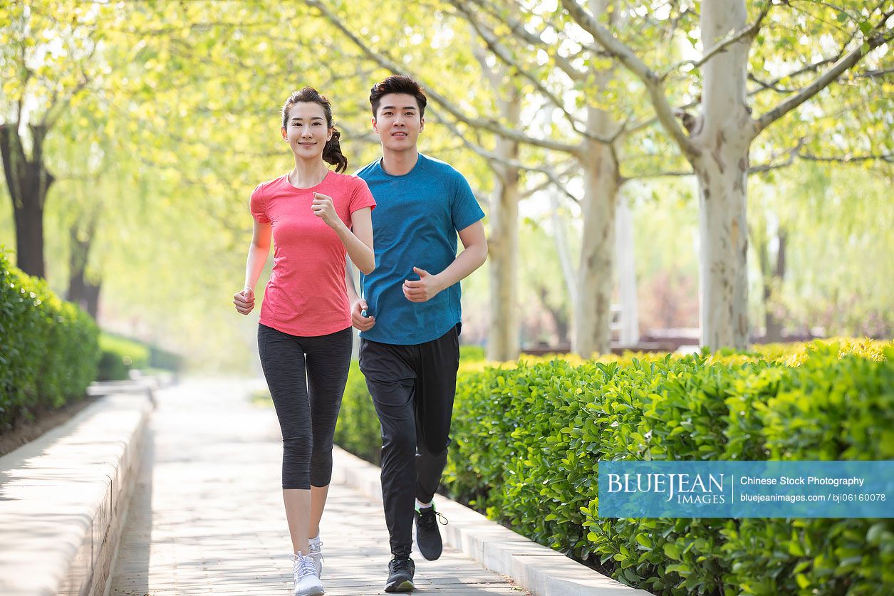 Happy young Chinese couple running in park