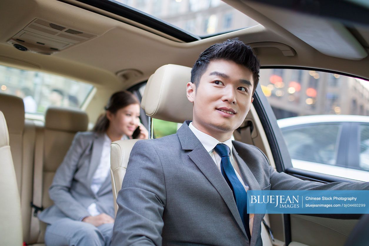 Chinese chauffeur driving car for a Chinese businesswoman