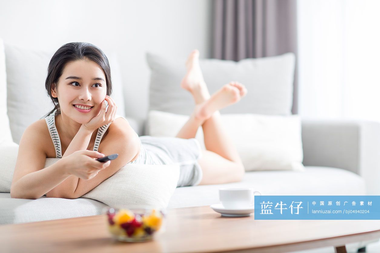 年轻女子在沙发上看电视