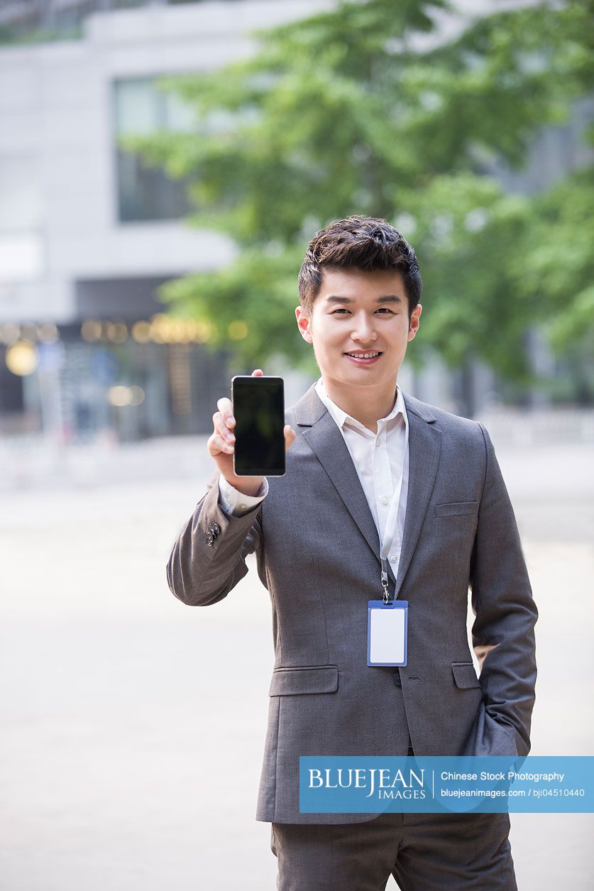 Young Chinese businessman showing smart phone