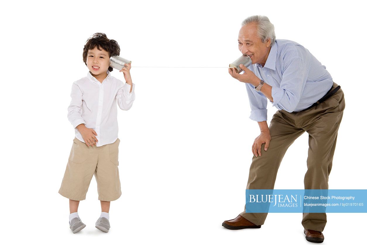 Chinese grandfather and grandson playing with a tin-phone
