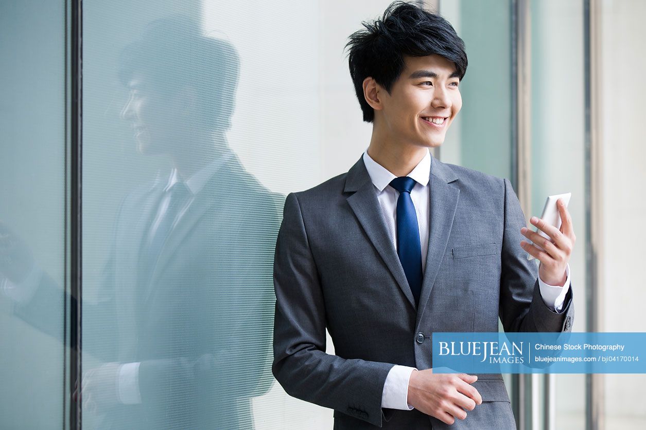 Young Chinese businessman holding mobile phone