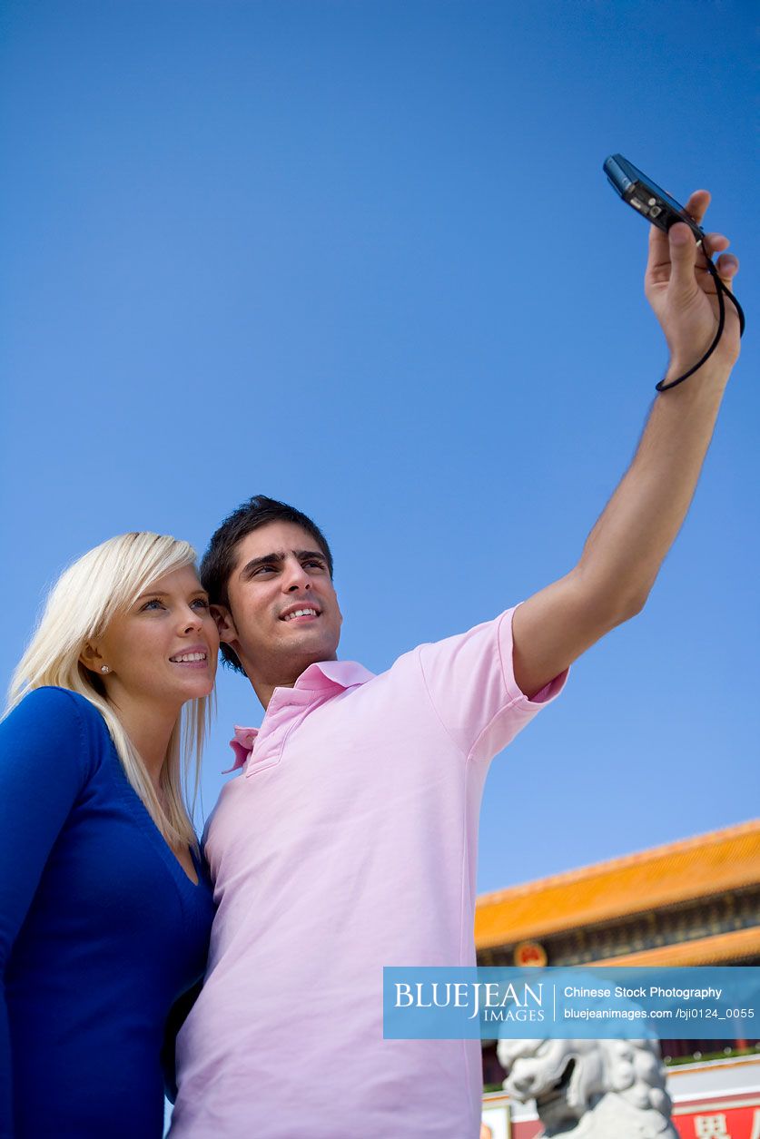 Young couple takes their own picture in front of Tiananmen Gate, Beijing, China