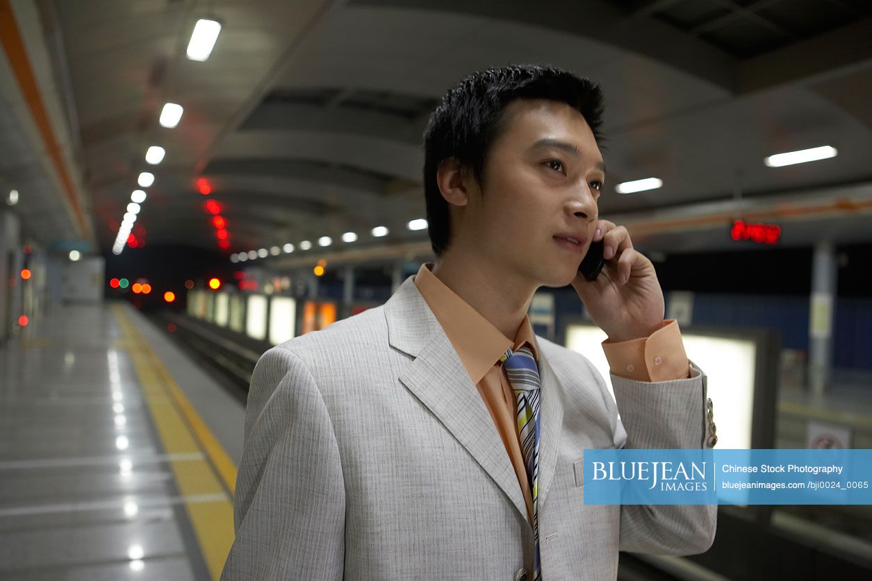 Chinese man talking on cell phone on train station