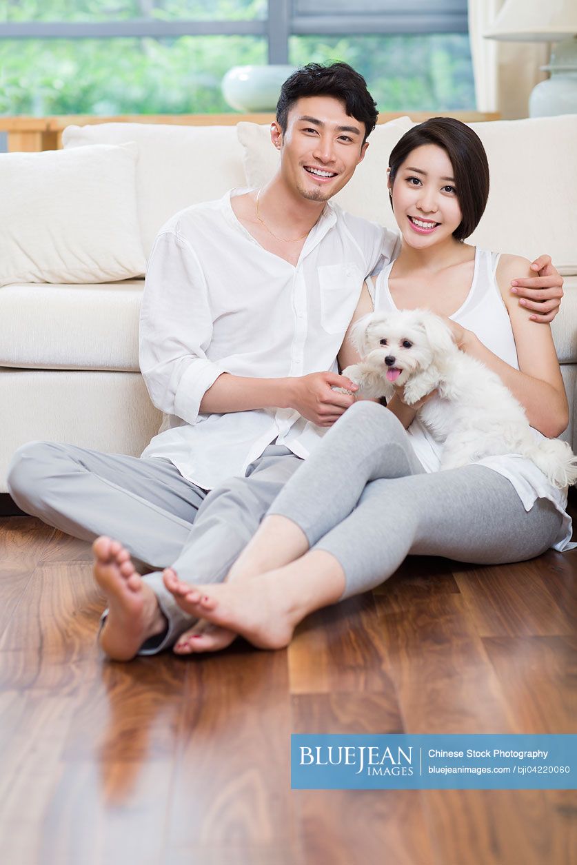 Cheerful young Chinese couple and a cute dog