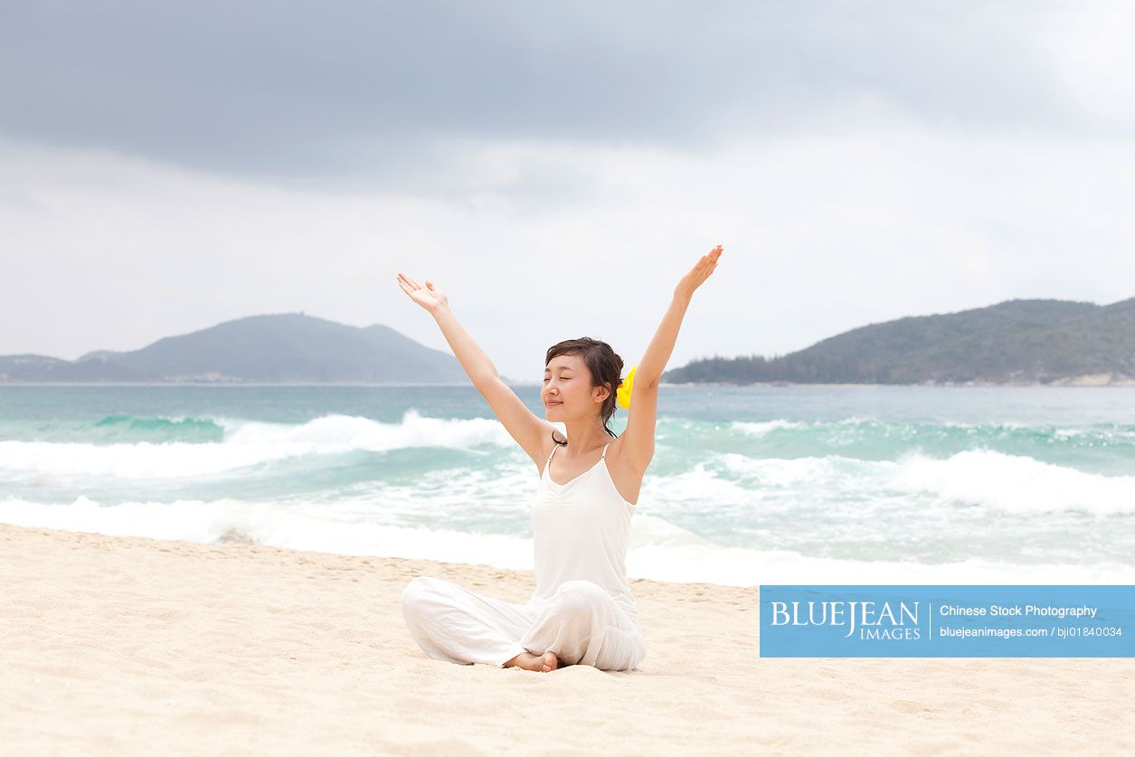 A woman practicing yoga at the beach