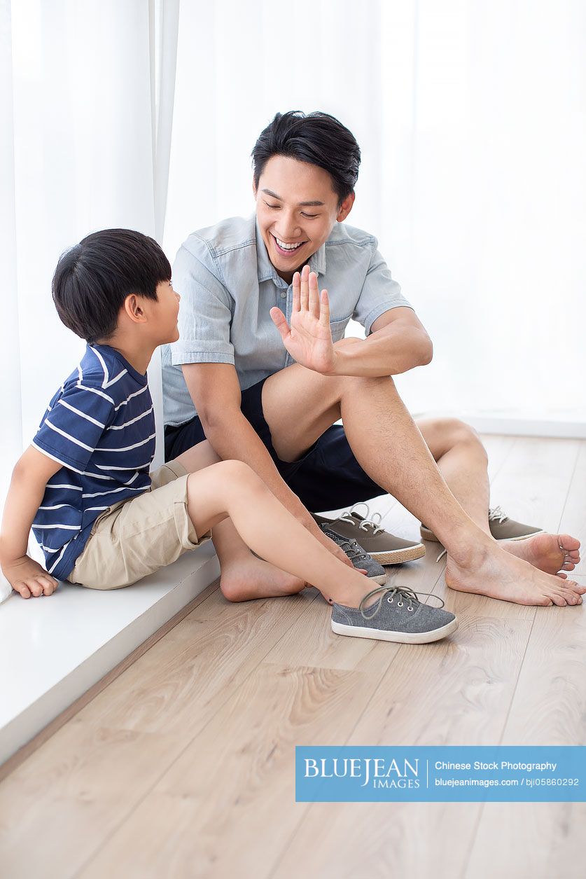 Chinese father teaching his son to tie shoelaces