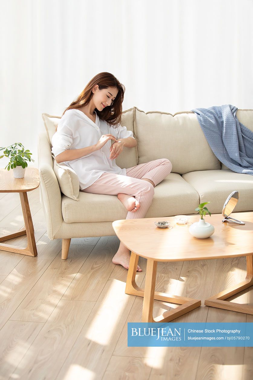 Young Chinese woman applying moisturizer at home