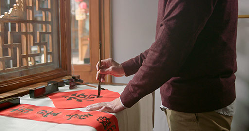 Happy senior Chinese man writing calligraphy on couplets,4K