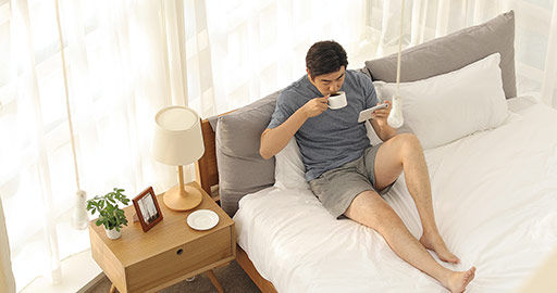 Happy young Chinese man playing mobile games in bedroom,4K