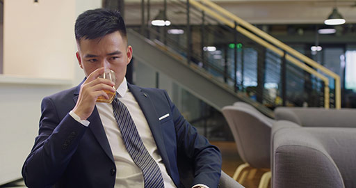 Confident Chinese businessman drinking alcohol in office,4K