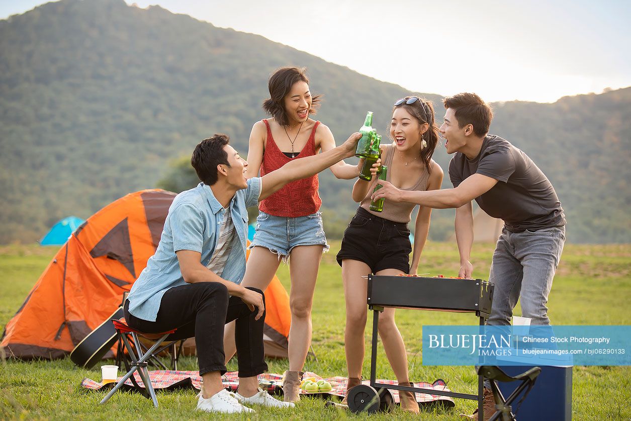 Happy young Chinese friends barbecuing outdoors