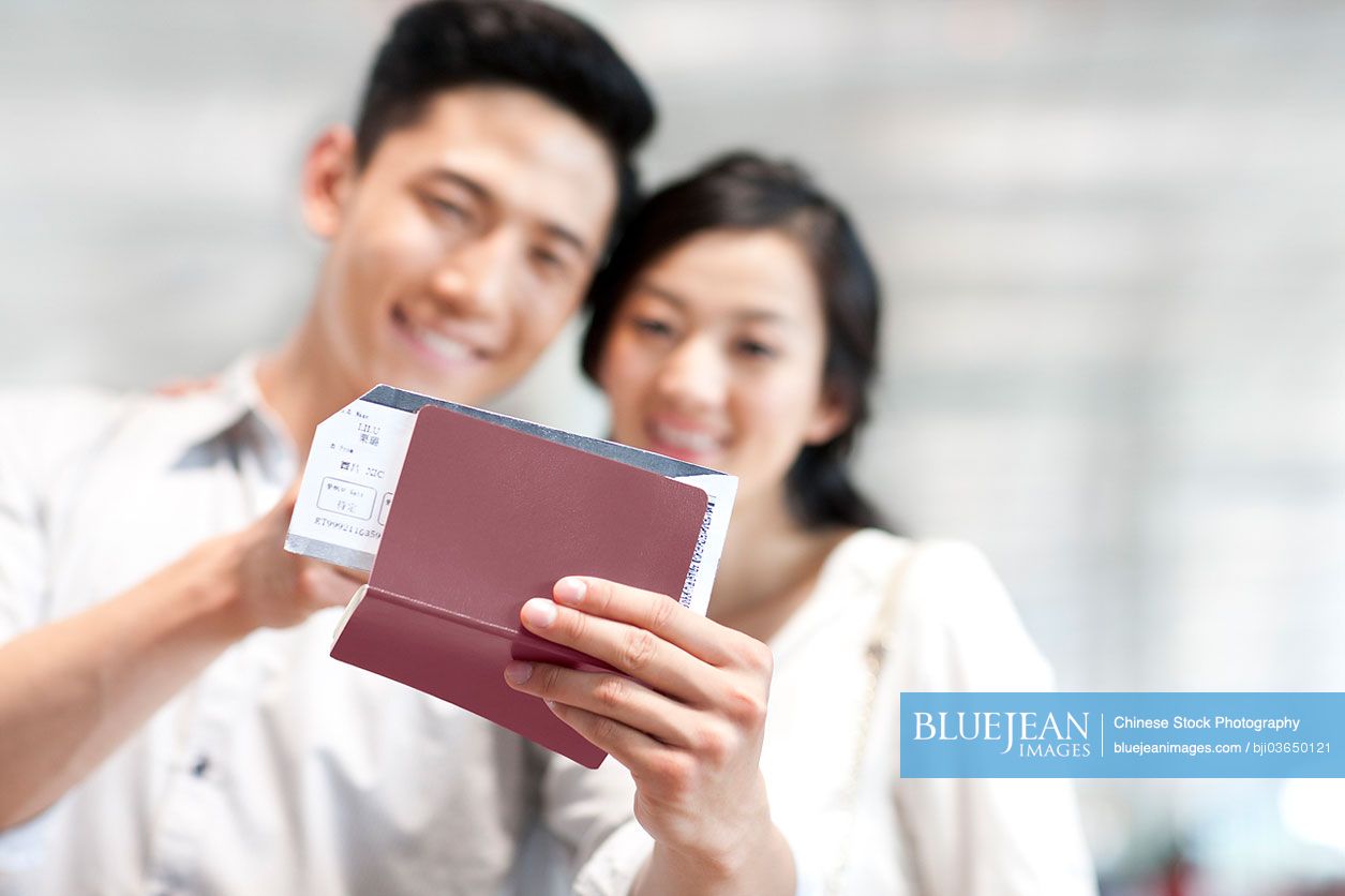 Young Chinese couple at the airport with flight tickets and passports