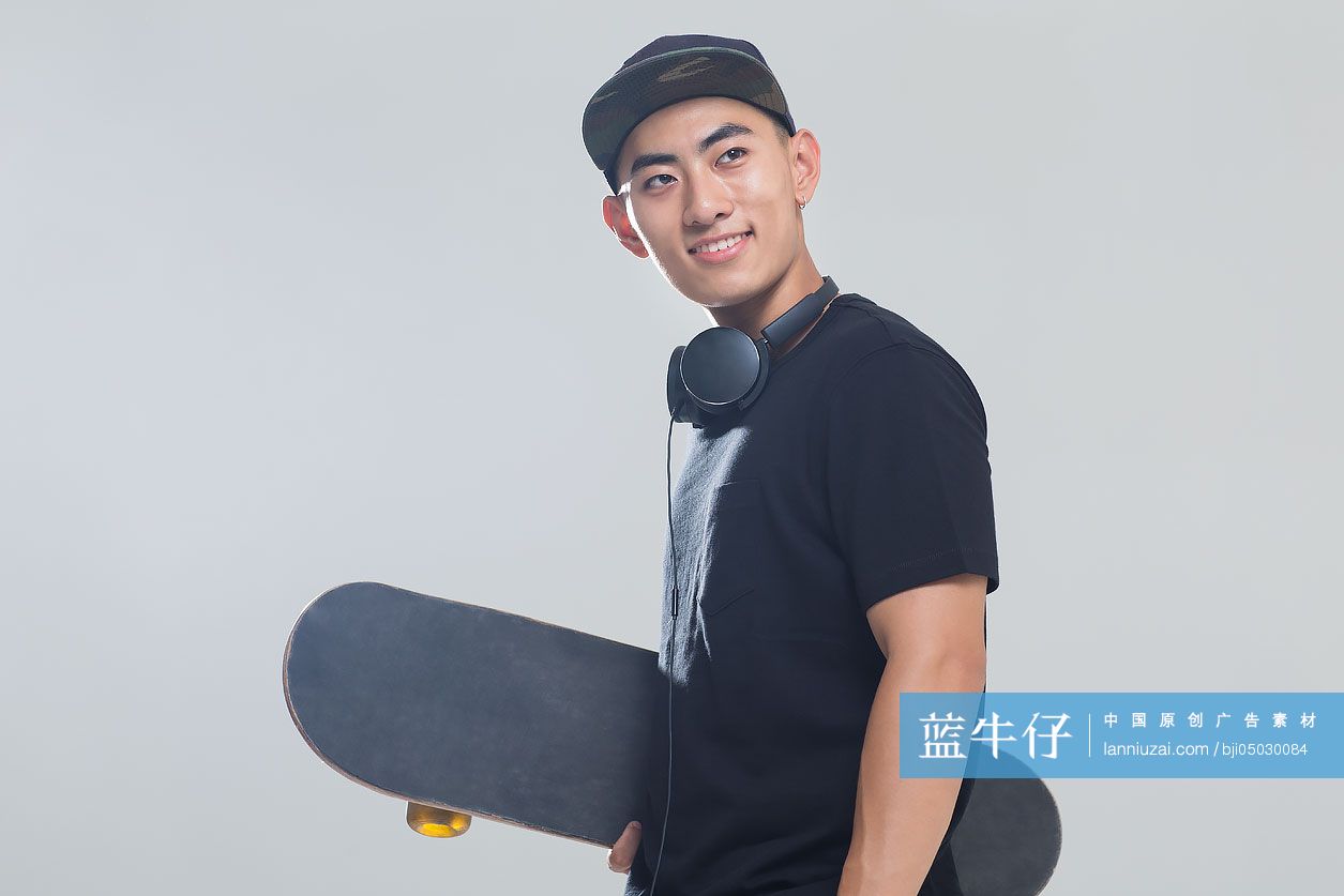 戴耳机的年轻男子手拿滑板