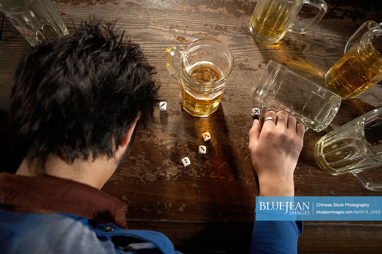 Tired young Chinese man sitting at a bar