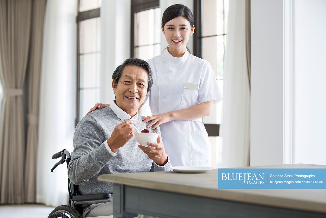 Chinese nursing assistant taking care of senior man in wheel chair