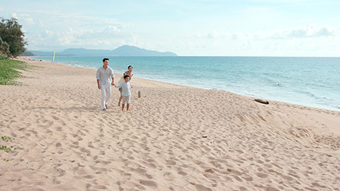 快乐的年轻家庭在沙滩散步