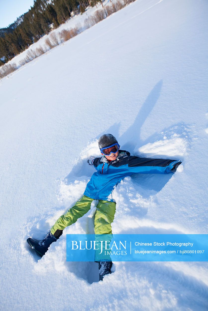 Little boy lying on snow ground