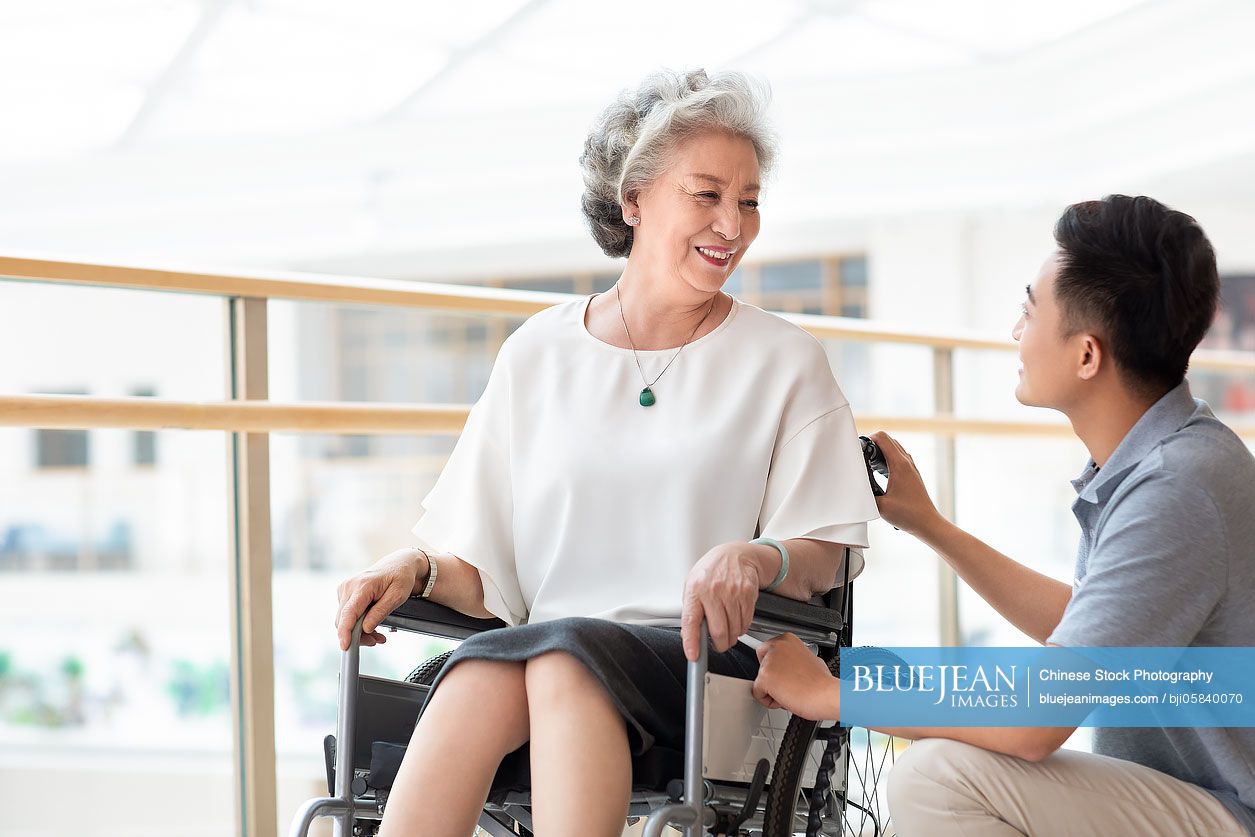 Chinese nursing assistant taking care of senior woman in wheelchair