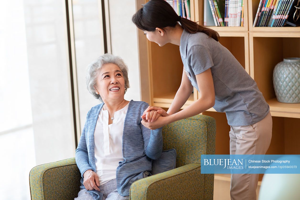 Chinese nursing assistant taking with senior woman in nursing home