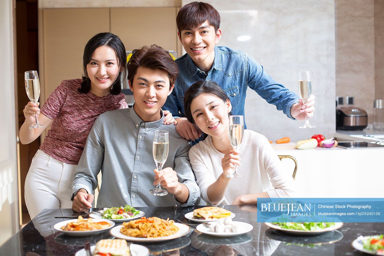 Young Chinese friends toasting at home