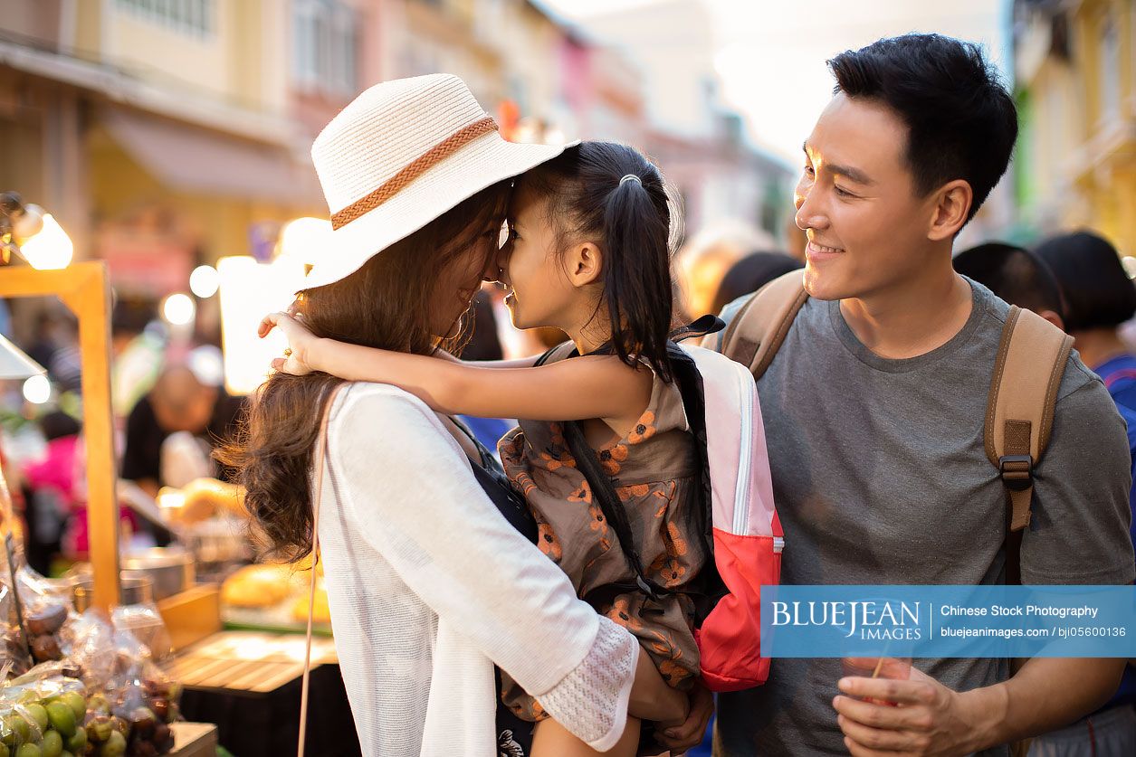 Happy young Chinese family relaxing in street market