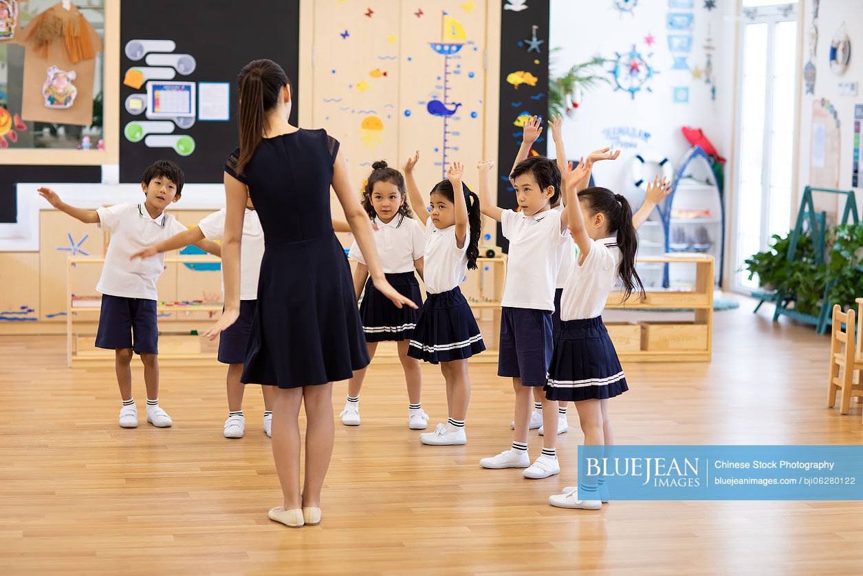 Chinese teacher teaching children dancing in classroom