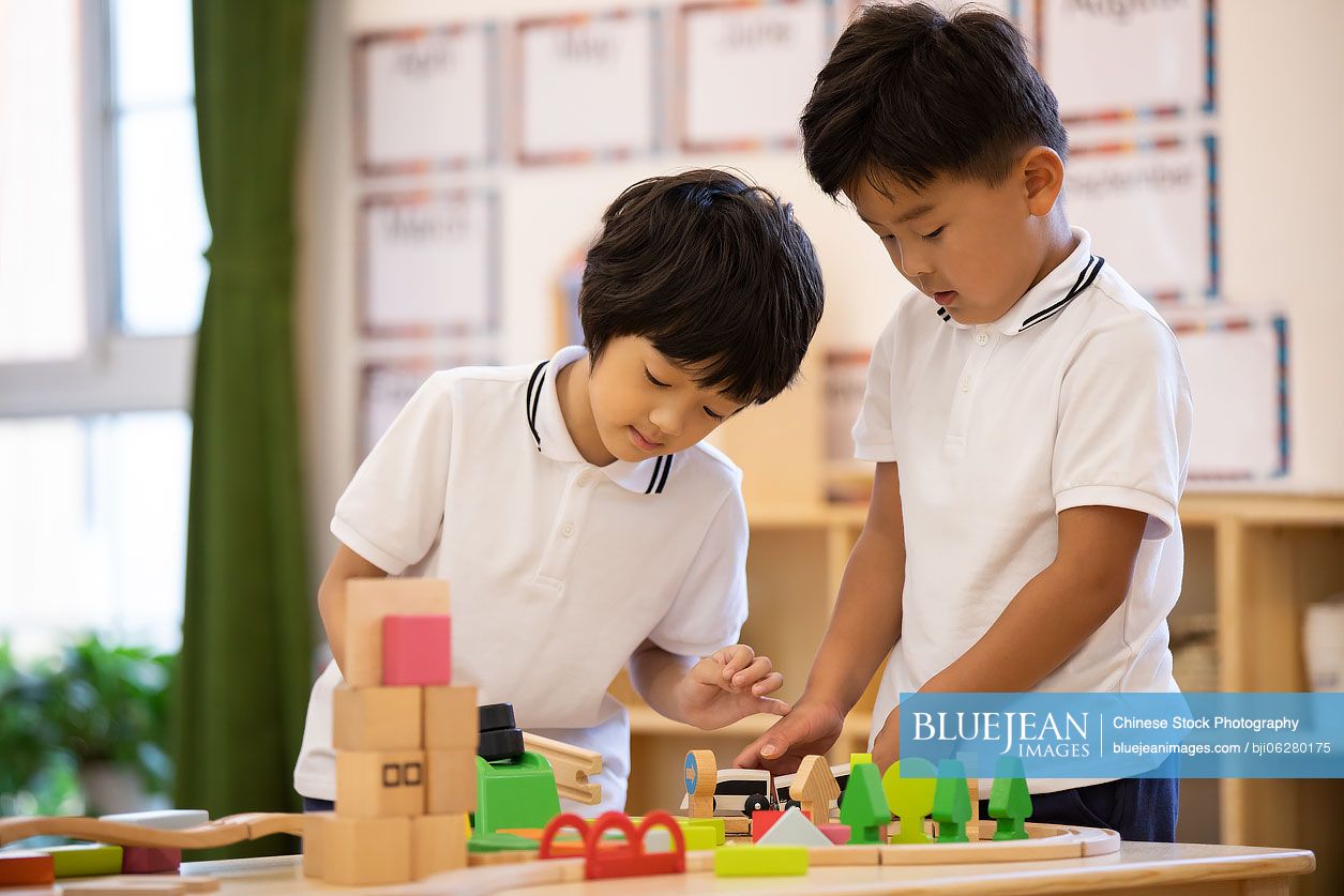 Little Chinese boys playing train set in classroom