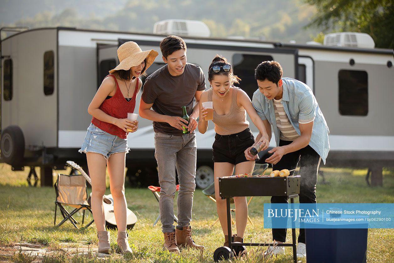 Happy young Chinese friends barbecuing outdoors