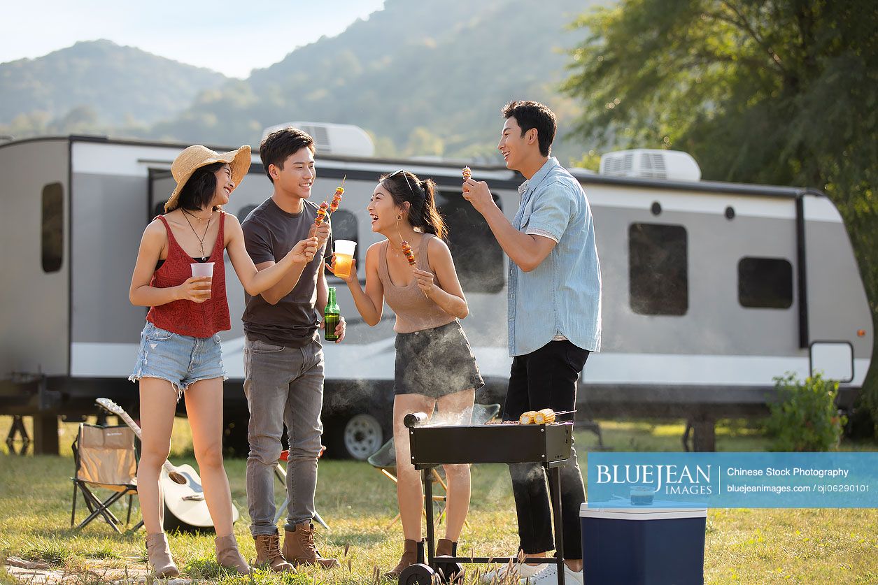 Happy young Chinese friends barbecuing outdoors