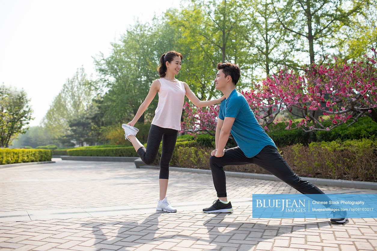 Happy young Chinese couple exercising in park