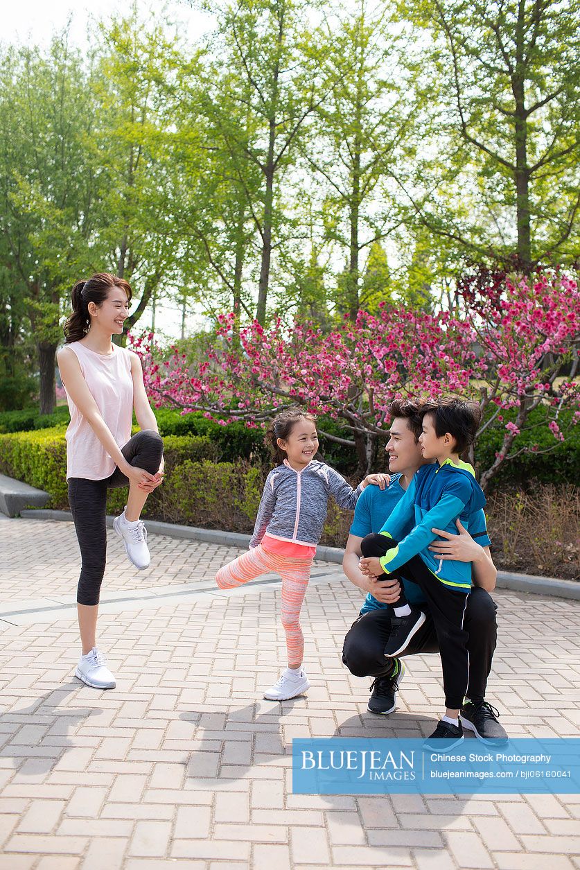 Happy young Chinese family exercising in park