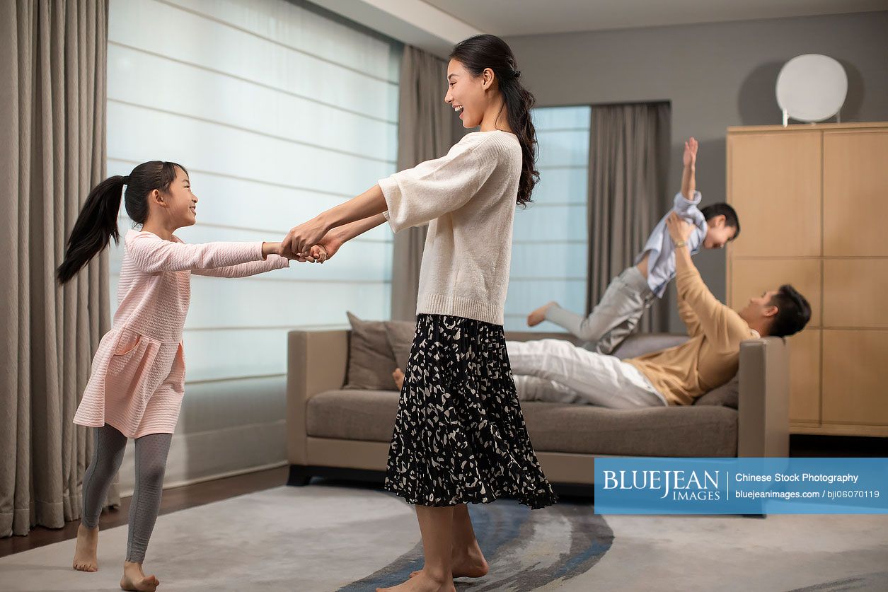 Happy young Chinese family having fun in living room