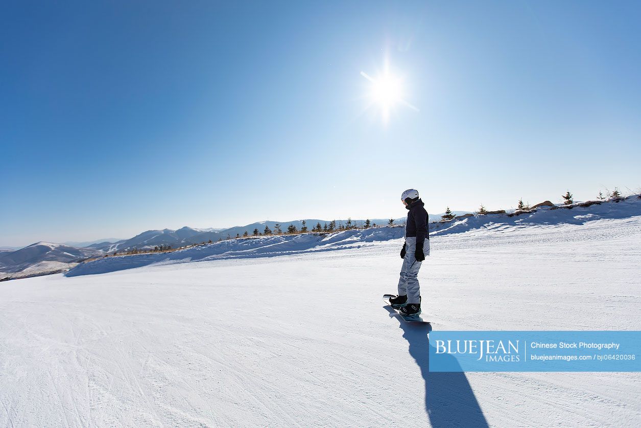 Young Chinese man snowboarding in ski resort