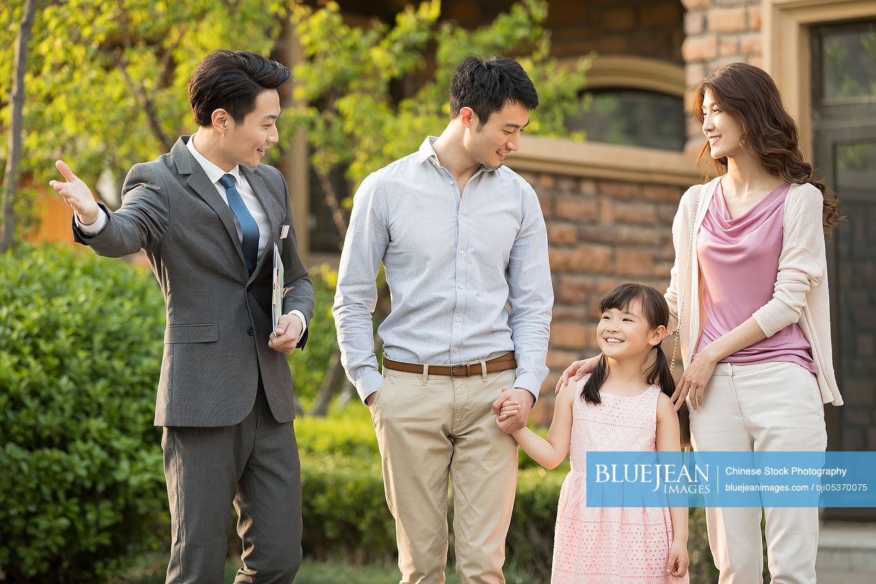 Happy young Chinese family talking with realtor