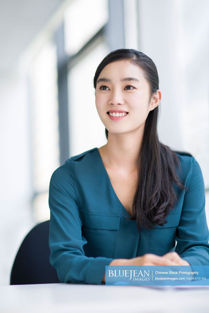 Young Chinese businesswoman thinking in office
