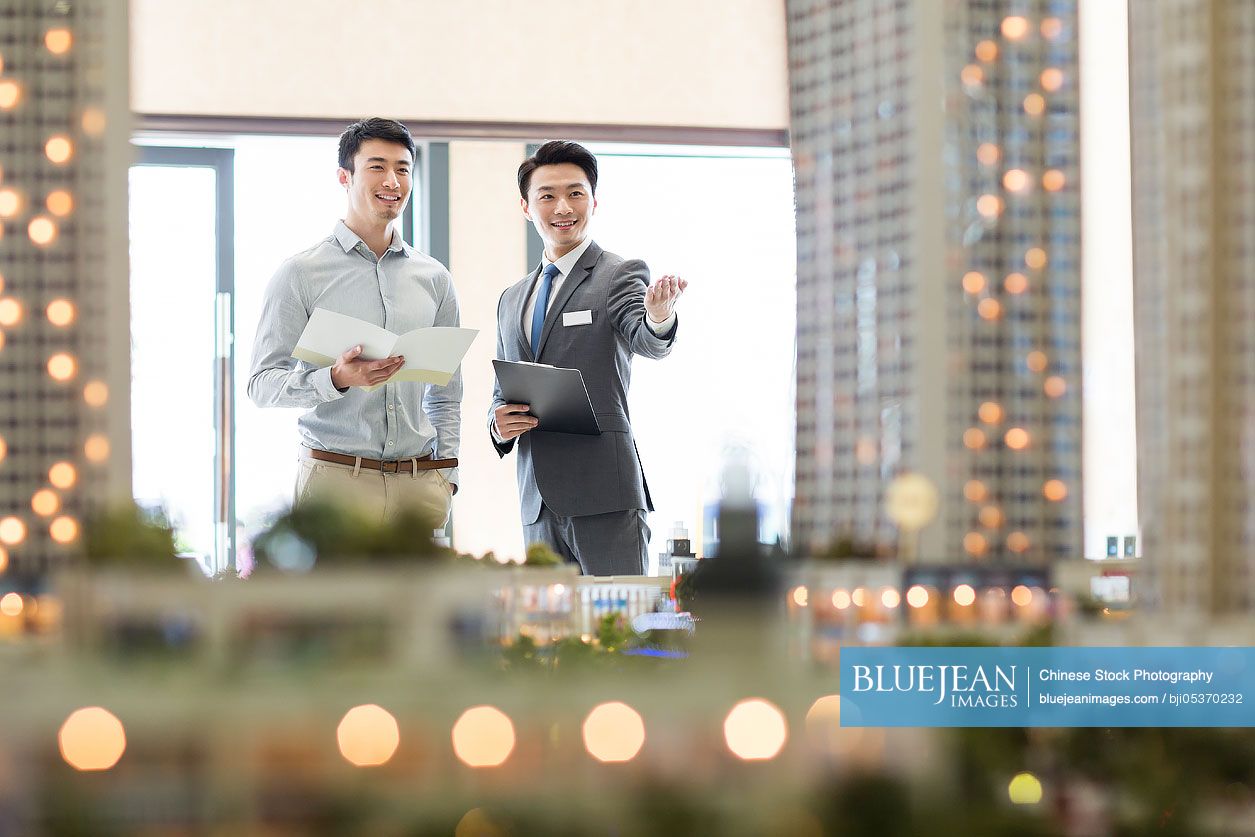 Chinese realtor showing architectural model to young manHighres stock