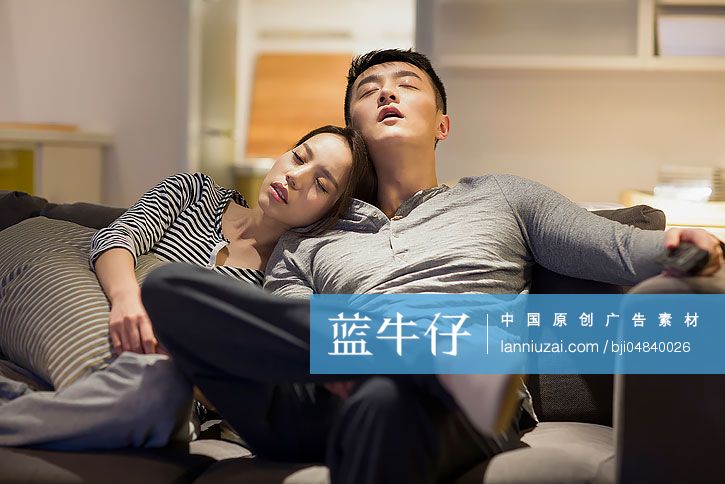 疲倦的年轻情侣在客厅沙发上睡觉