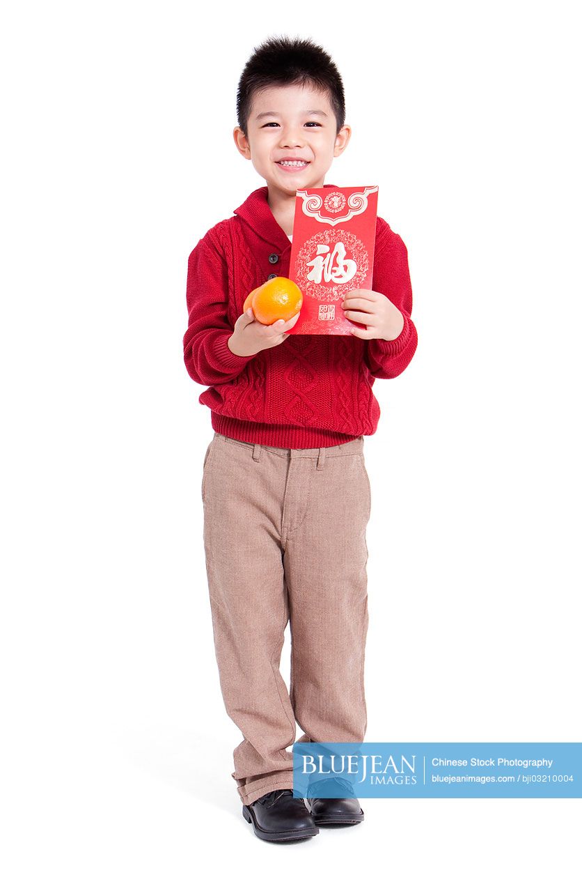 Happy Chinese boy holding red pockets and oranges