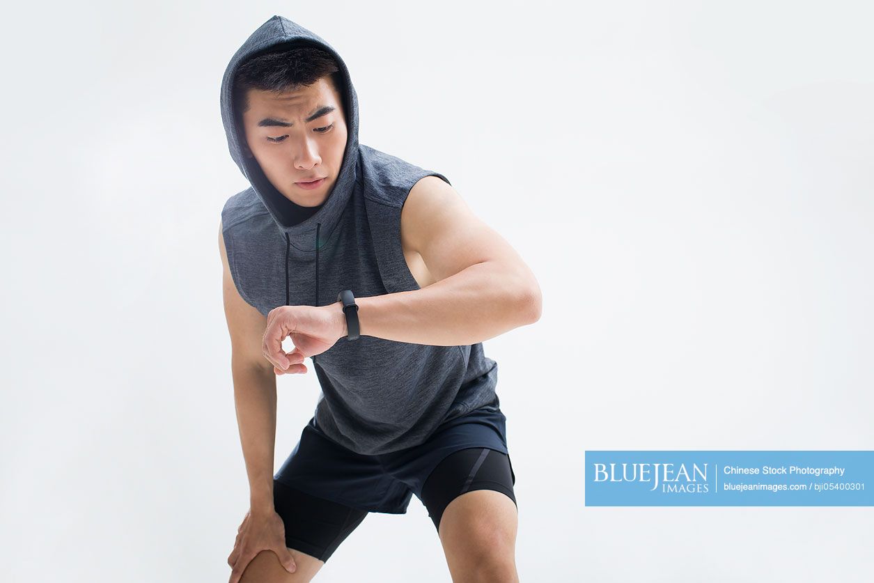 Young Chinese man checking smart watch after running