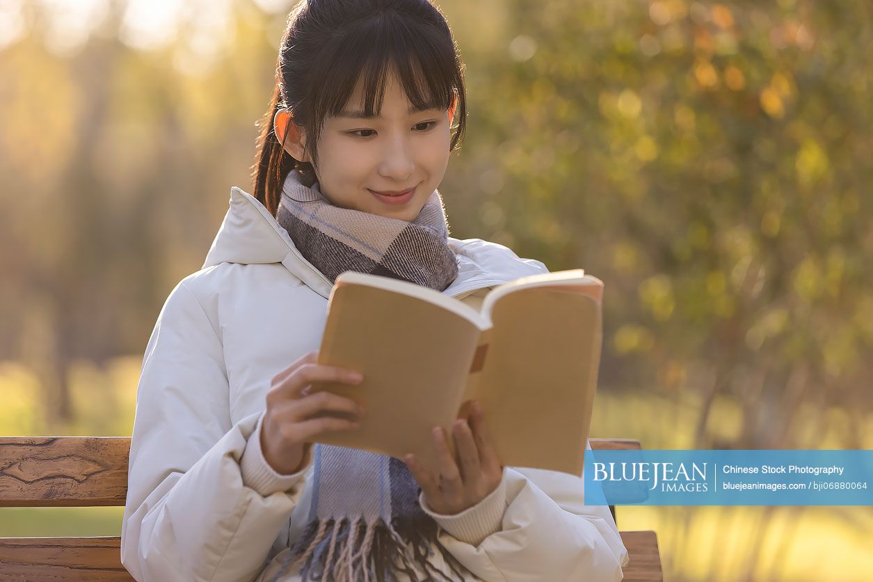 Happy Chinese college student reading on campus