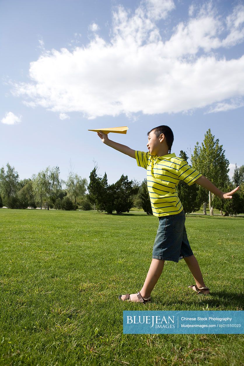 Chinese boy playing with a paper airplane
