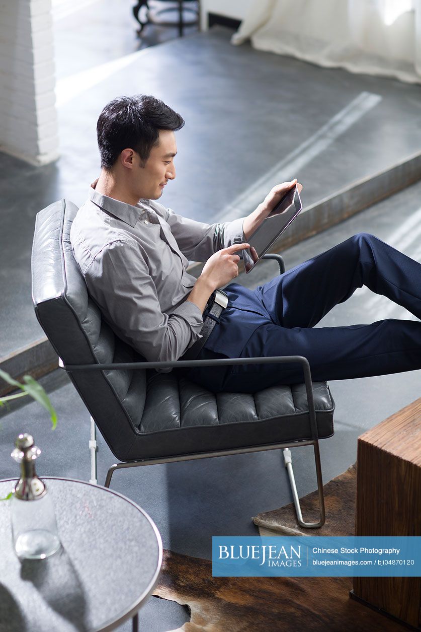 Young Chinese man using digital tablet in office