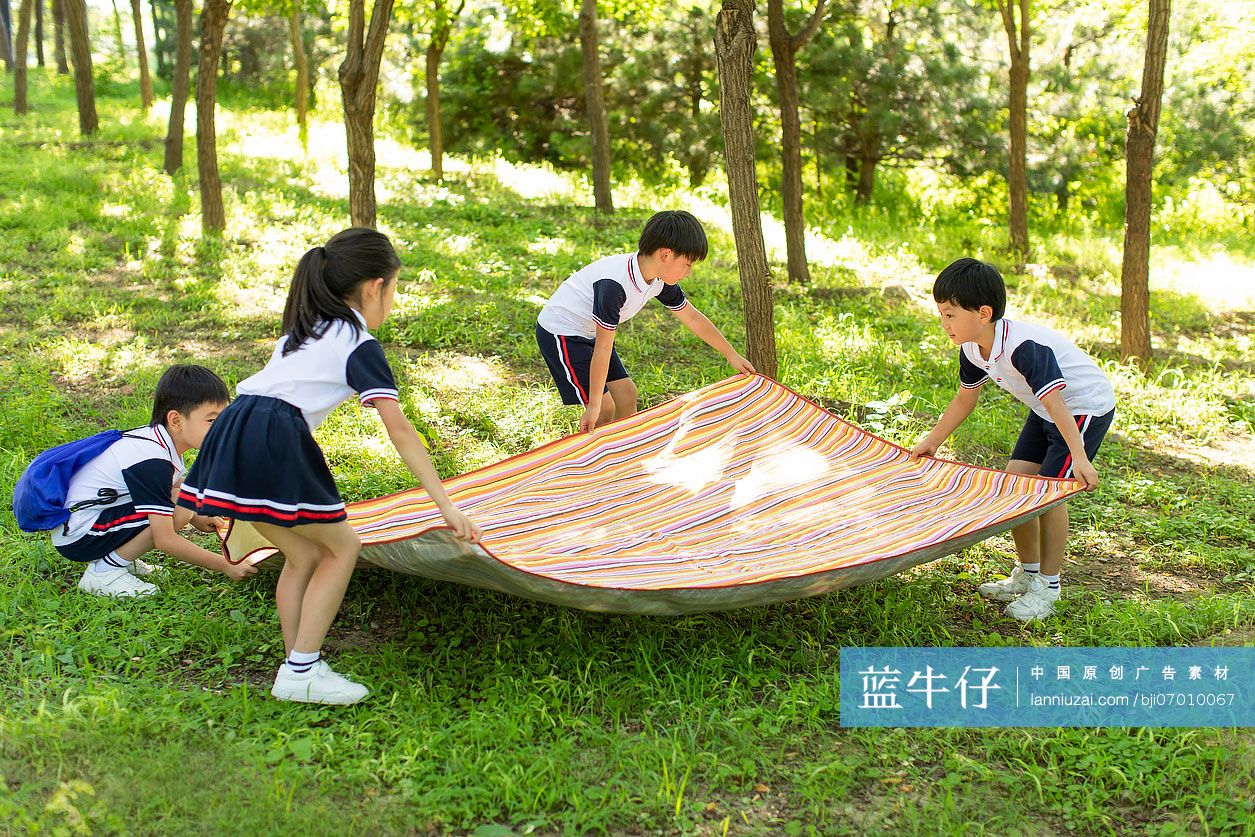 快乐的小学生铺野餐垫