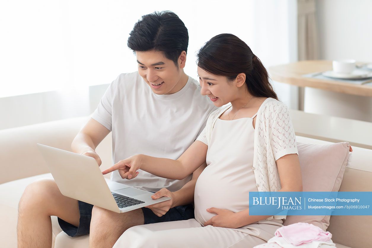 Young Chinese pregnant woman with husband shopping online